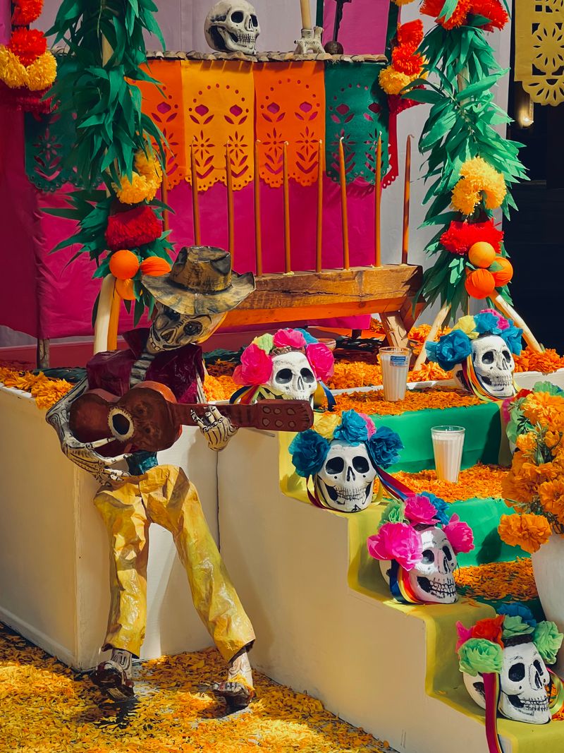 A colorful Día de Muertos altar with marigolds, candles and decorated skulls