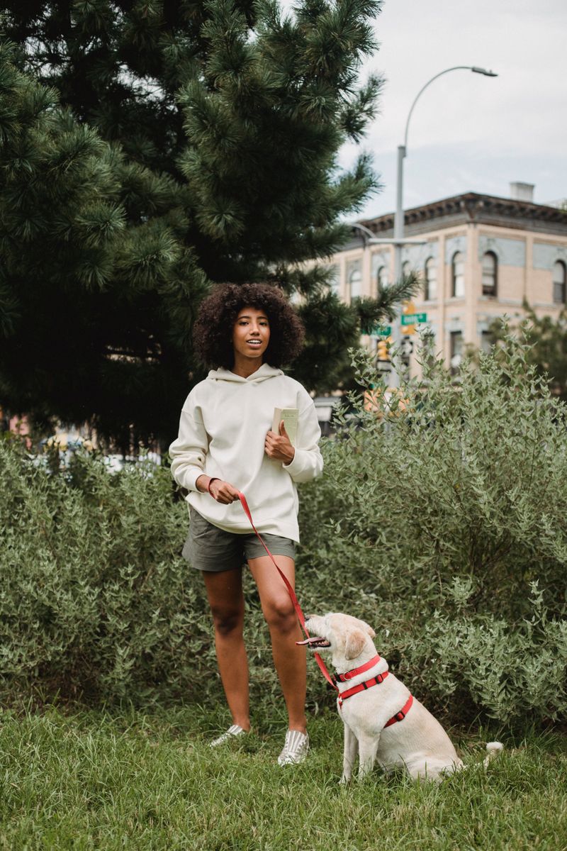 A smiling woman with a happy dog on a leash in a park